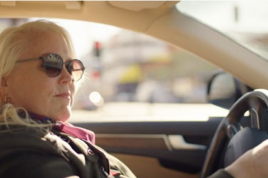 TEPEZZA patient Jeanne T. wearing sunglasses and driving a car